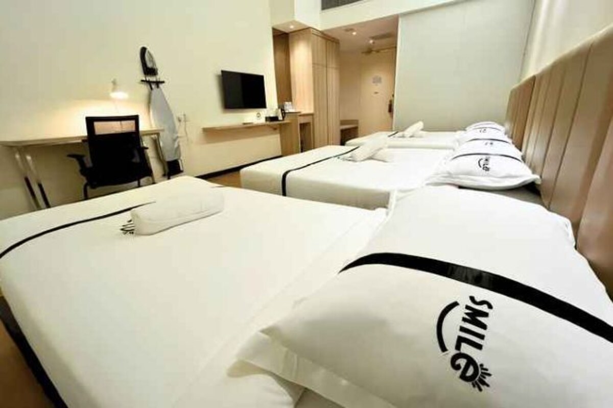 Een hotelkamer met twee bedden, een bureau, een stoel, een televisie en een raam.