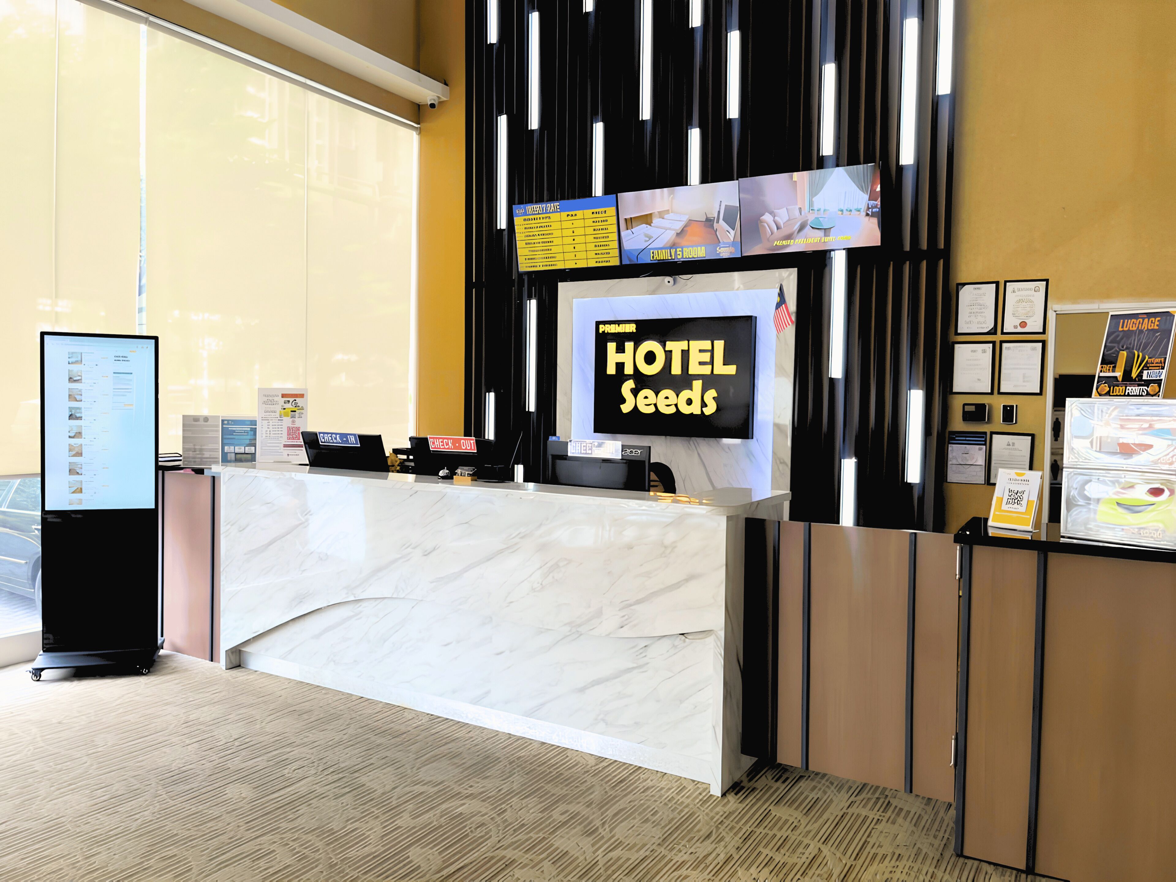 A hotel reception desk with a digital display, a check-in/out counter, and a sign indicating the hotel name.