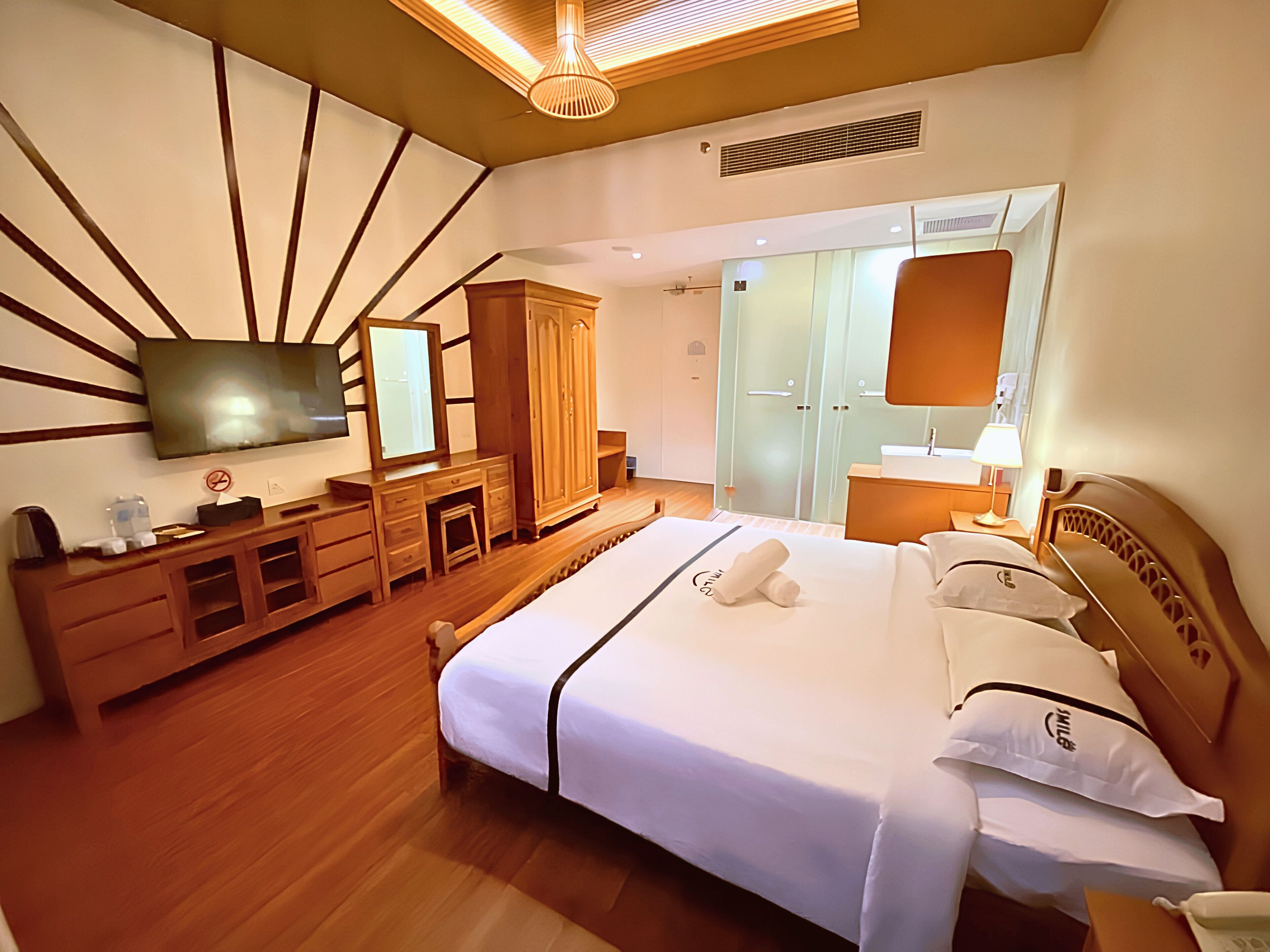 Een hotelkamer met een bed, een aan de muur bevestigde televisie, een kledingkast en een spiegel.