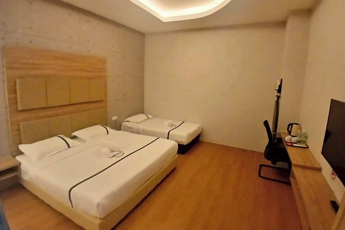 Ein Hotelzimmer mit zwei Betten, einem Holzkopfende, einem Flachbildfernseher und einer Gitarre.