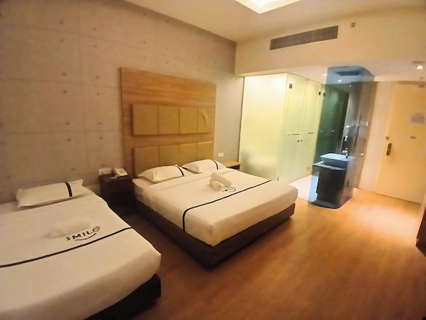 Une chambre d’hôtel avec deux lits, un grand miroir et une armoire.
