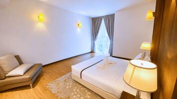 A hotel room with a bed, a sofa, a lamp, and a window with curtains.