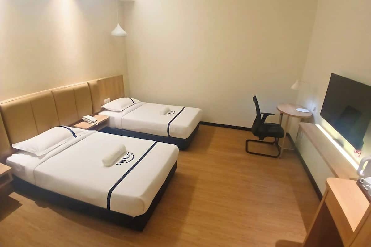 Ein Hotelzimmer mit zwei Betten, einem Fernseher, einem kleinen Tisch und einem Stuhl.