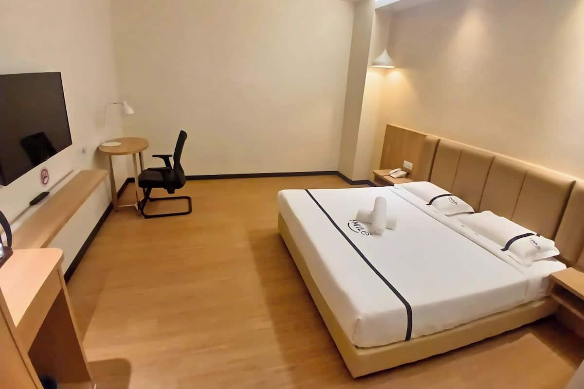 Ein Hotelzimmer mit Bett, Schreibtisch, Stuhl, Fernseher und Lampe.