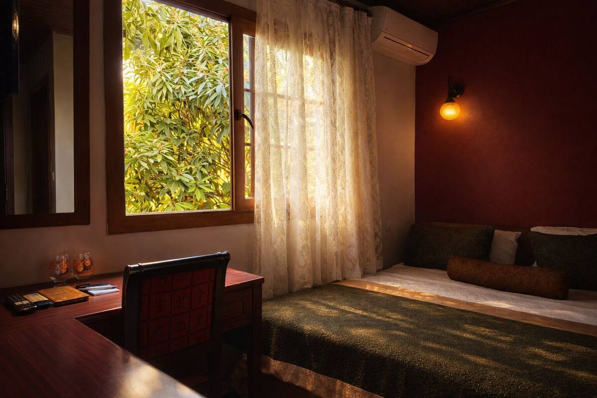 A room with a bed, a desk, a window with curtains, and an air conditioning unit.