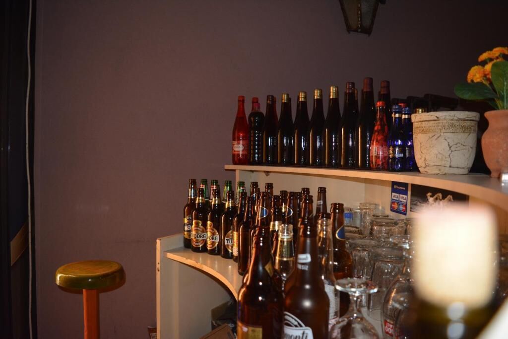 Una zona de bar con estantes llenos de botellas de cerveza y vasos.