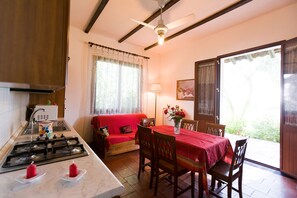 A cozy kitchen with a gas stove, a red sofa, and a dining table set for four. - Orange Park (Misterbianco)