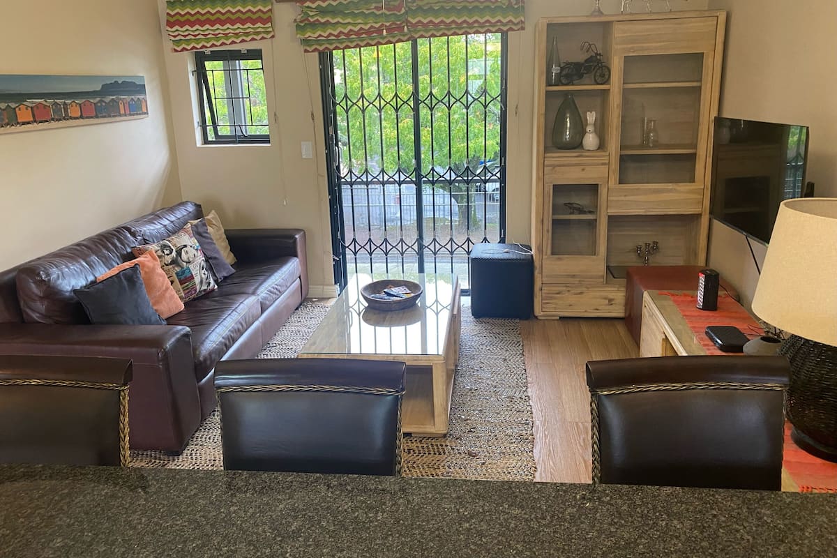 A living room with a brown leather sofa, a coffee table, and a TV on a wooden stand.