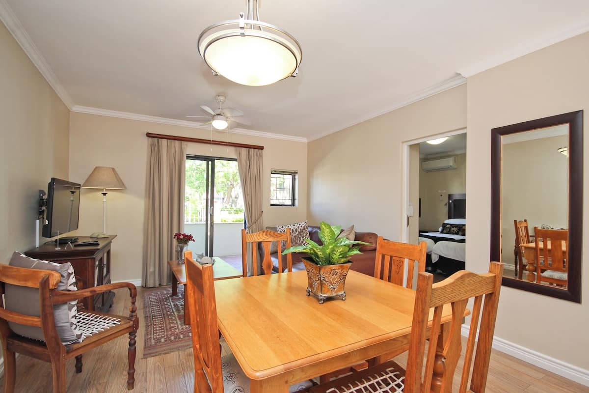 A dining area with a wooden table, chairs, a ceiling fan, and a large mirror on the wall.
