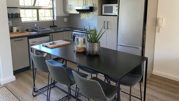 Una cocina moderna con una isla central, taburetes de bar, un microondas y un refrigerador.