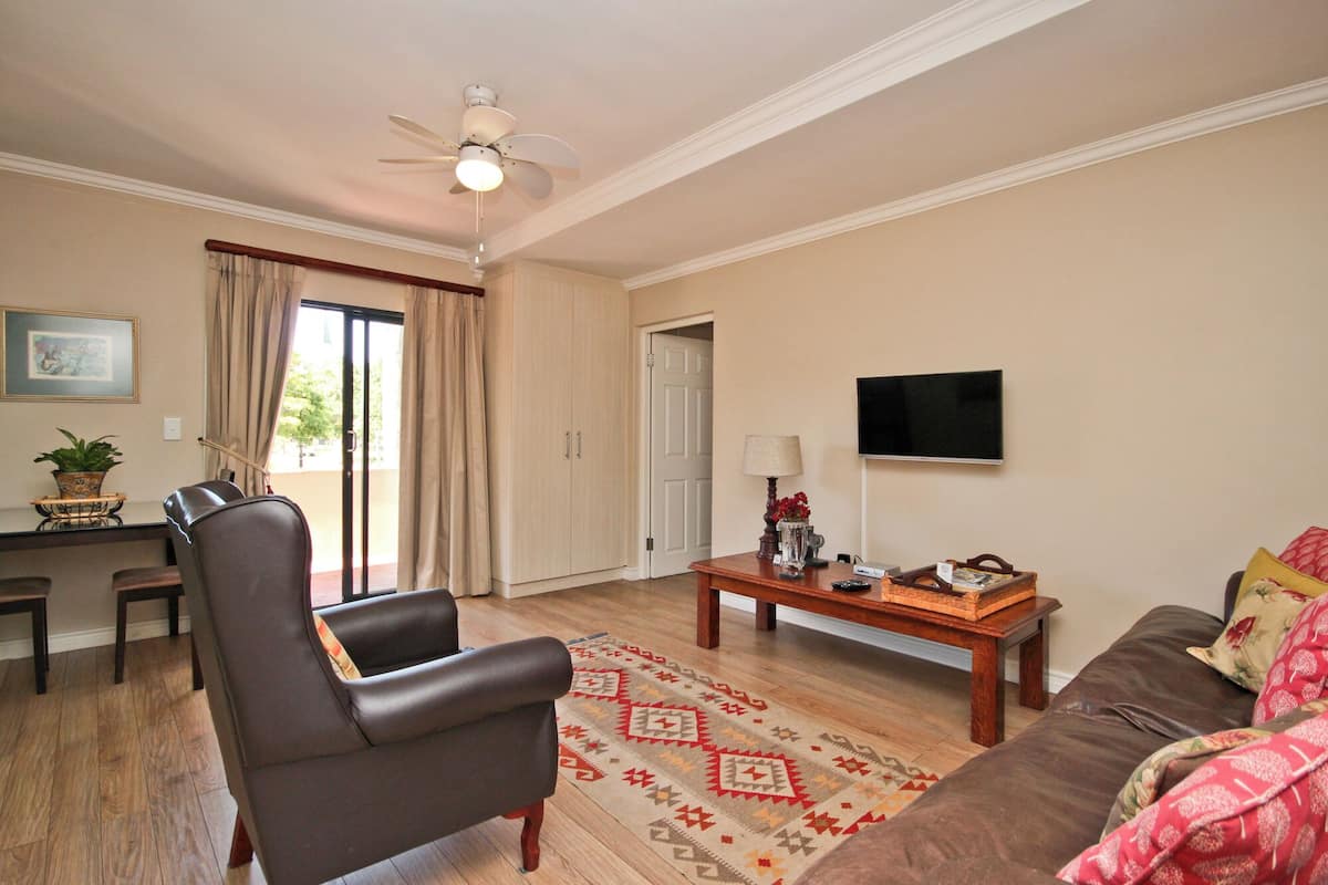 A living room with a ceiling fan, a TV mounted on the wall, a sofa, a coffee table, and a chair.
