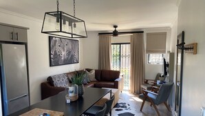 Una sala de estar moderna con comedor, un sofá, una mesa de centro y un ventanal con cortinas.