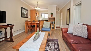 Una sala de estar con una mesa de centro de madera, un sofá de cuero rojo y un comedor con sillas y una mesa de madera.