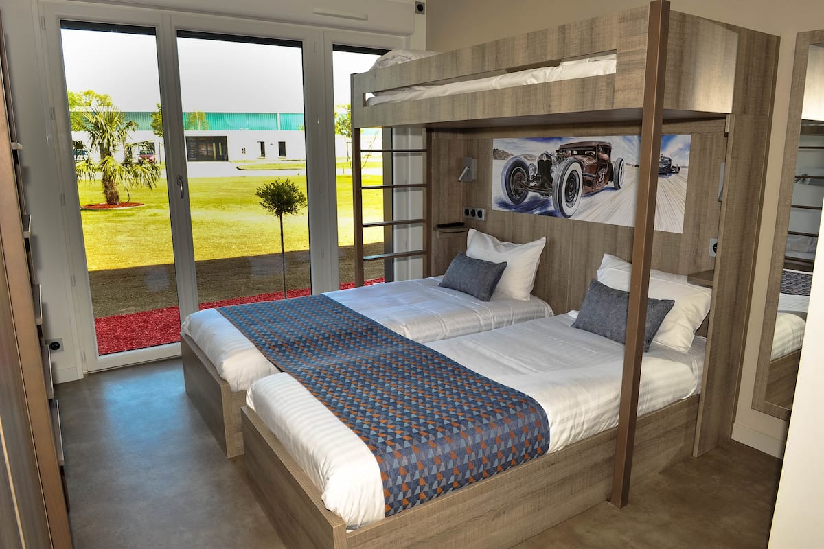 A modern bedroom with a large bed, a view of the outdoors, and a wooden headboard.