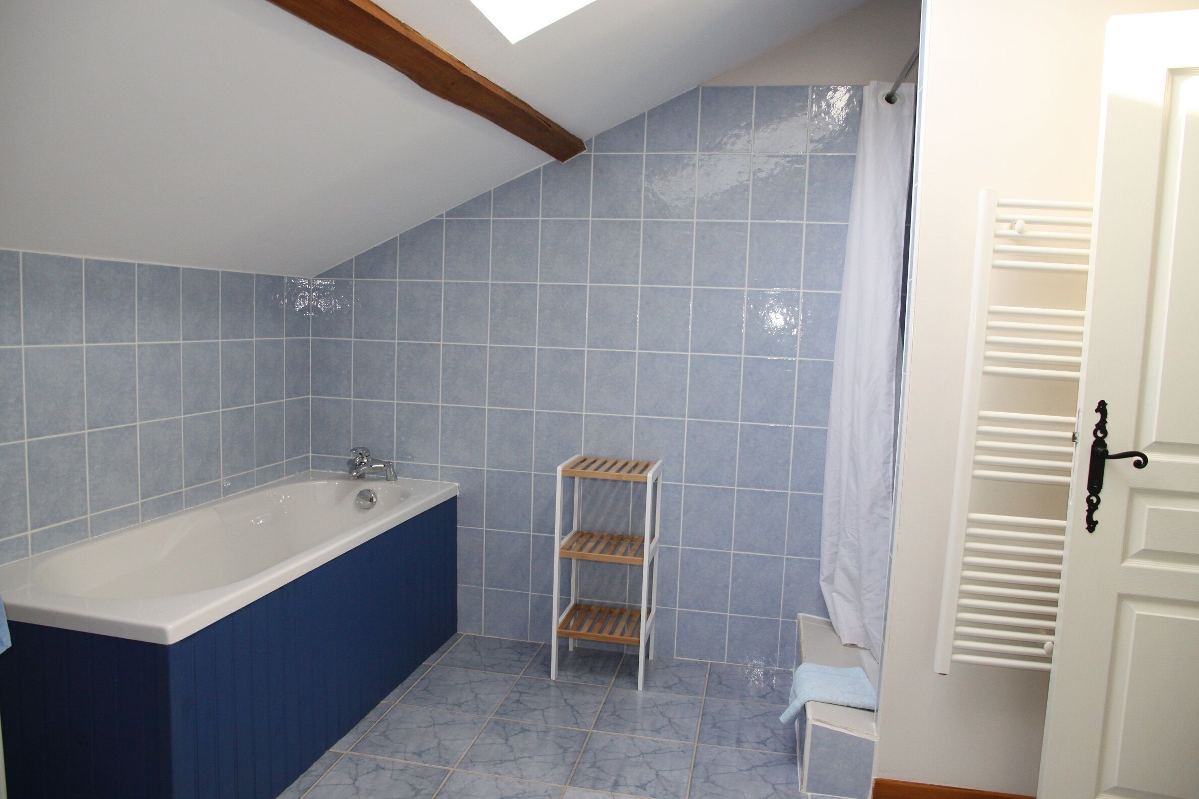 Une salle de bain avec une baignoire, une étagère et un rideau de douche.