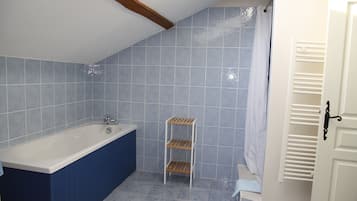 Une salle de bain avec une baignoire, une étagère et un rideau de douche.