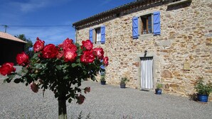 A stone building with a gravel courtyard, a tree with red flowers, and blue shutters on the windows. - Gîtes et Chambres d'Hôtes Peyrecout Tarn (Laparrouquial)
