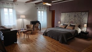 A bedroom with a bed, two chairs, a desk, and a piano. - Gîtes et Chambres d'Hôtes Peyrecout Tarn (Laparrouquial)