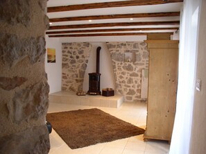 Une pièce aux murs de pierre, avec un meuble en bois, une cheminée et un tapis marron.