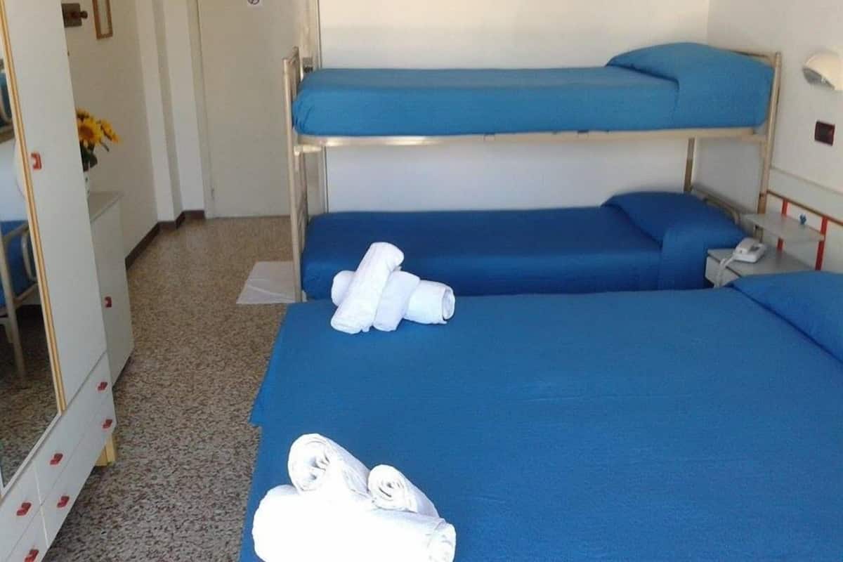 Una habitación de hotel con literas, una mesita de noche con lámpara y un espejo.