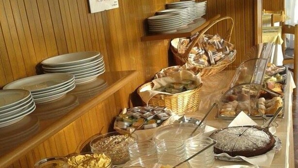 A buffet setup with plates, bowls, and various food items. - Hotel Goya (Rimini)