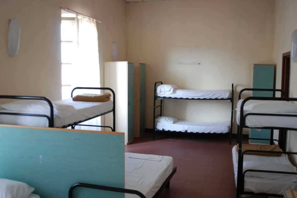 Un dormitorio con literas, una ventana y un refrigerador.