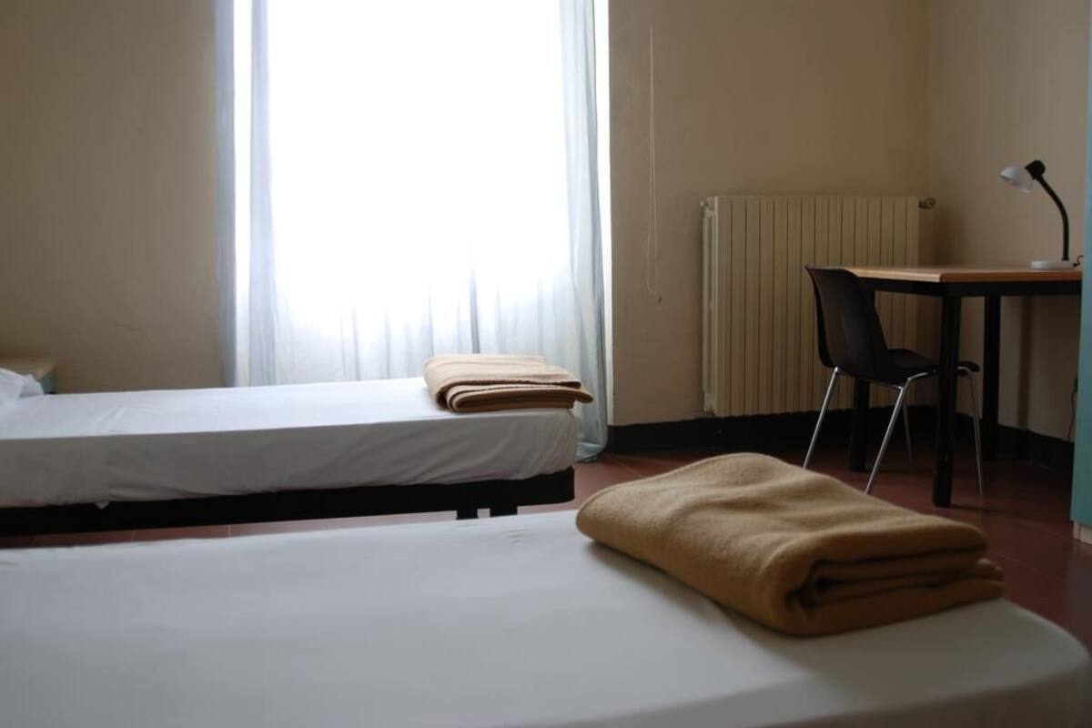 Habitación de hotel con dos camas, un escritorio y una silla.