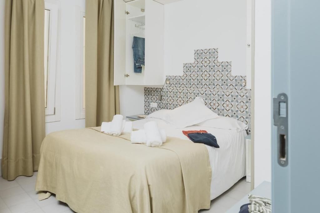 A hotel room with a bed, a wardrobe, and a bathroom visible through an open door.