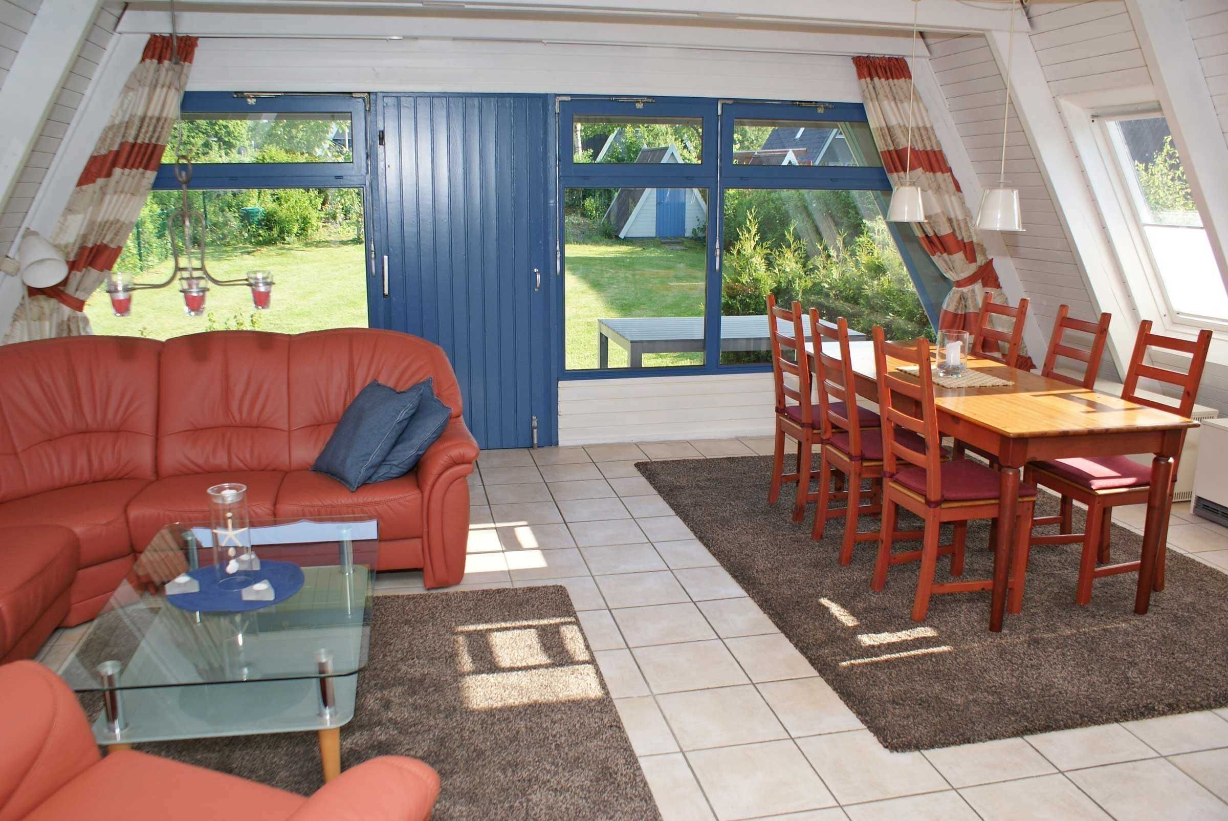 Ein gemütliches Wohnzimmer mit einem roten Sofa, einem Glastisch und einem Essbereich mit Holzstühlen und einem Tisch.