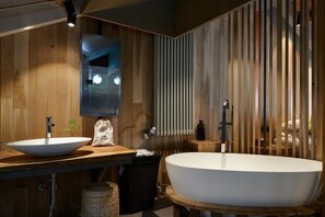 Un baño moderno con paneles de madera, una bañera independiente grande y un lavabo doble con espejo.