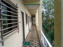 Un pasillo con ventanas de rejas, piso estampado y un tapete verde que dice “WELCOME”.