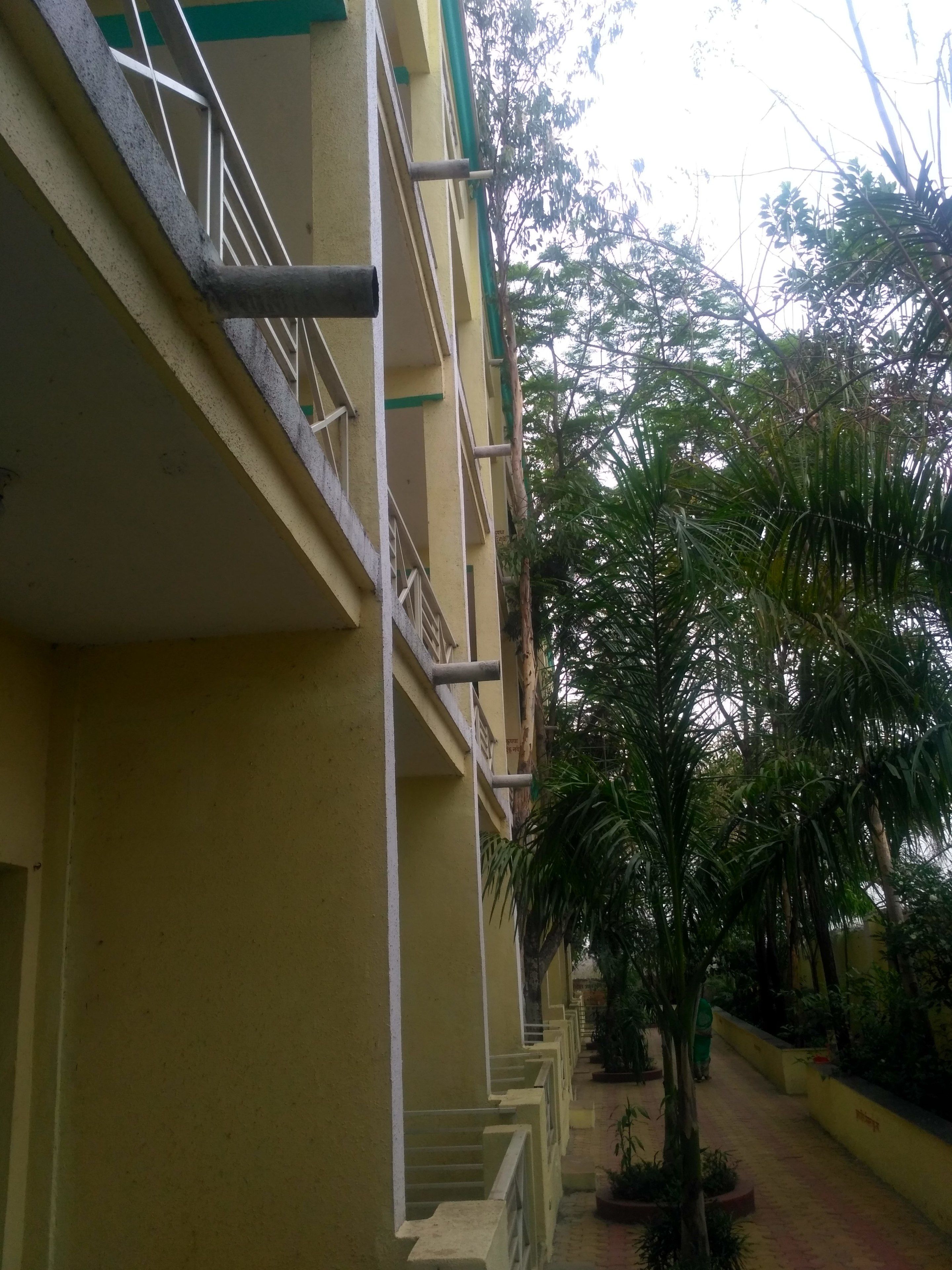 A multi-story building with balconies, a central staircase, and surrounding greenery.