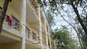 Un edificio de varios pisos con balcones, rodeado de árboles y follaje.