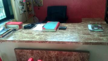 A reception desk with a computer, a telephone, and various items on the counter.