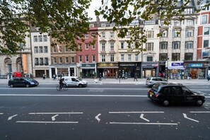 A street view with buildings, shops, and a cyclist.