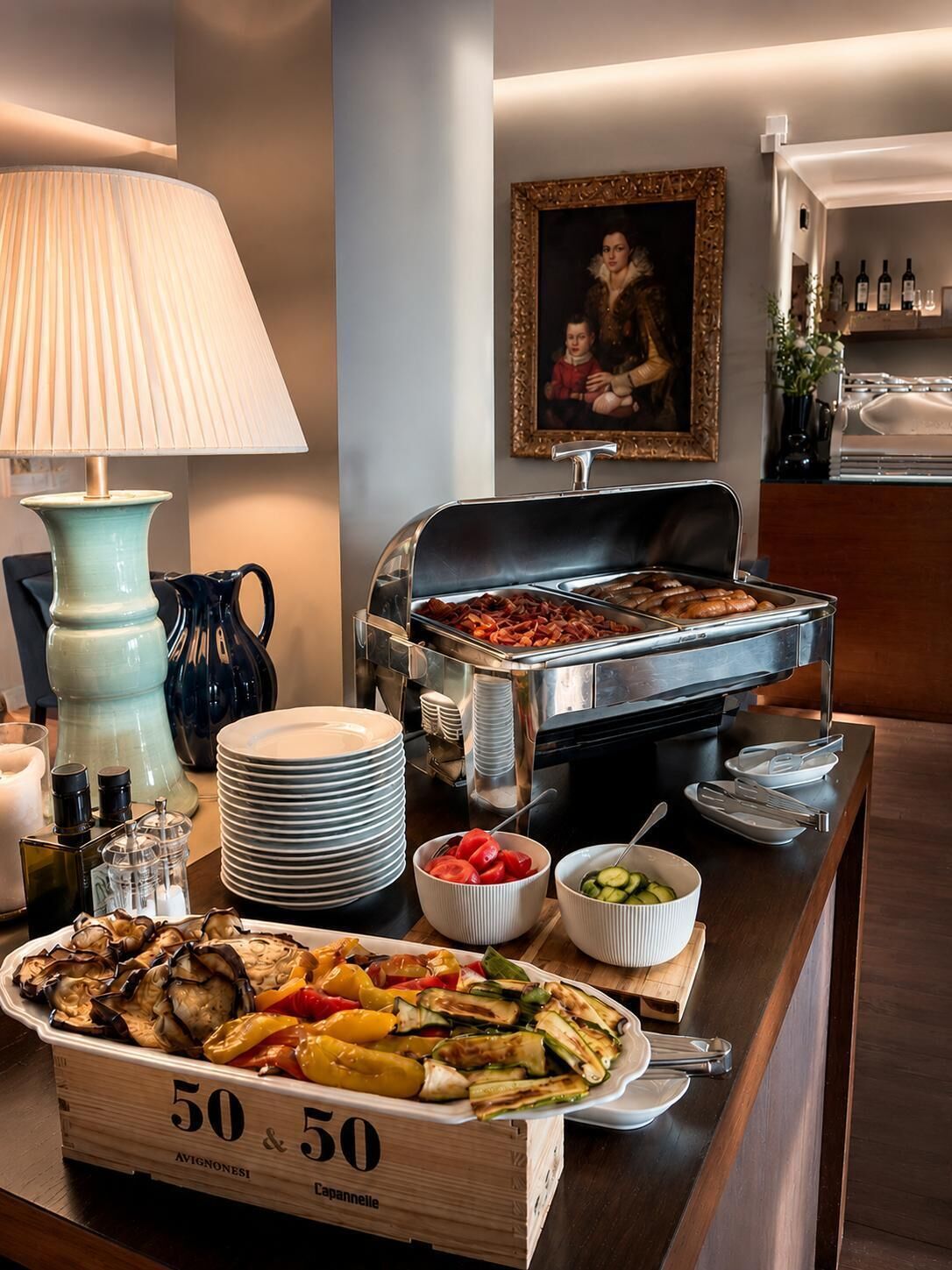 Un'impostazione buffet con diversi piatti, una lampada e un quadro incorniciato appeso al muro.