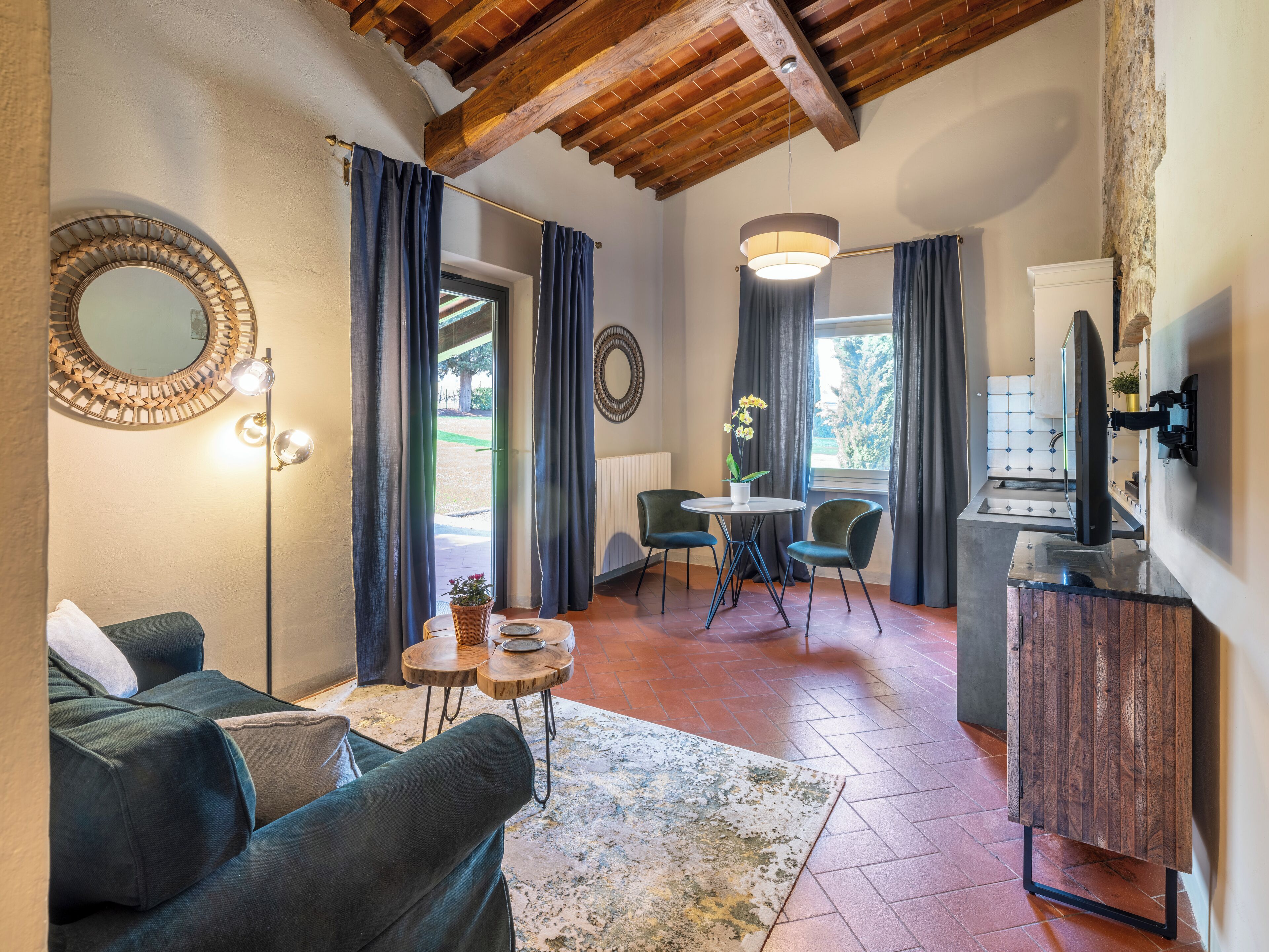 A cozy living room with a sofa, a small table with a vase, and a dining area with chairs.
