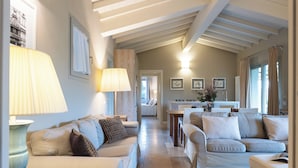 A spacious living area with a high ceiling and exposed beams, featuring a sofa set, a coffee table, and a dining table. - Borgo Iesolana Country Retreat (Bucine)