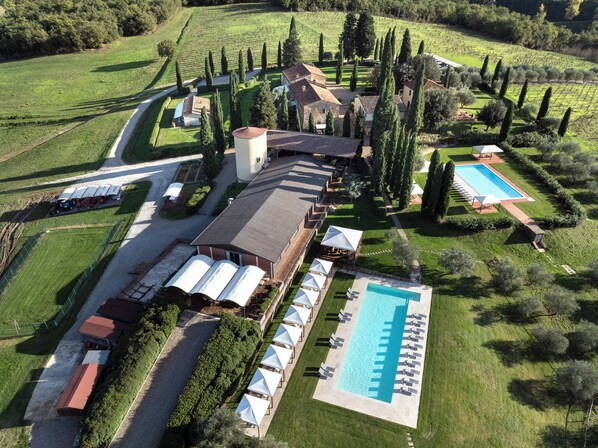 An aerial view of a resort with multiple buildings, a swimming pool, and well-maintained gardens.