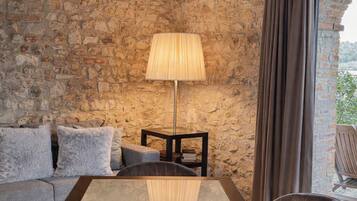Una habitación acogedora con pared de piedra, techo de madera, una mesa con sillas, una lámpara y un sofá.