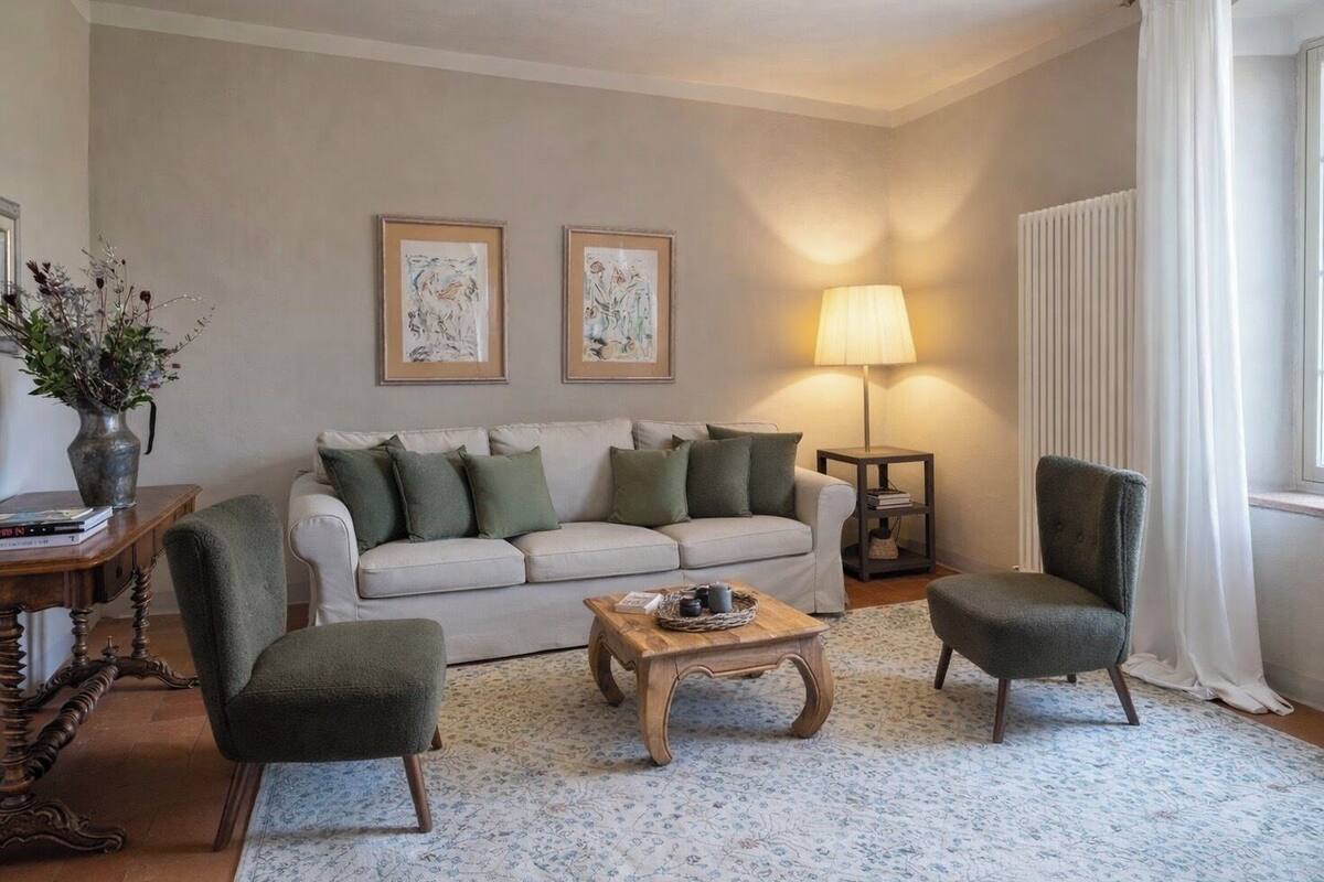 A living room with a sofa, two armchairs, a coffee table, a lamp, and framed artwork on the wall.
