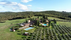 A villa with a swimming pool, surrounded by olive groves and vineyards, set in a hilly landscape. - Borgo Iesolana Country Retreat (Bucine)