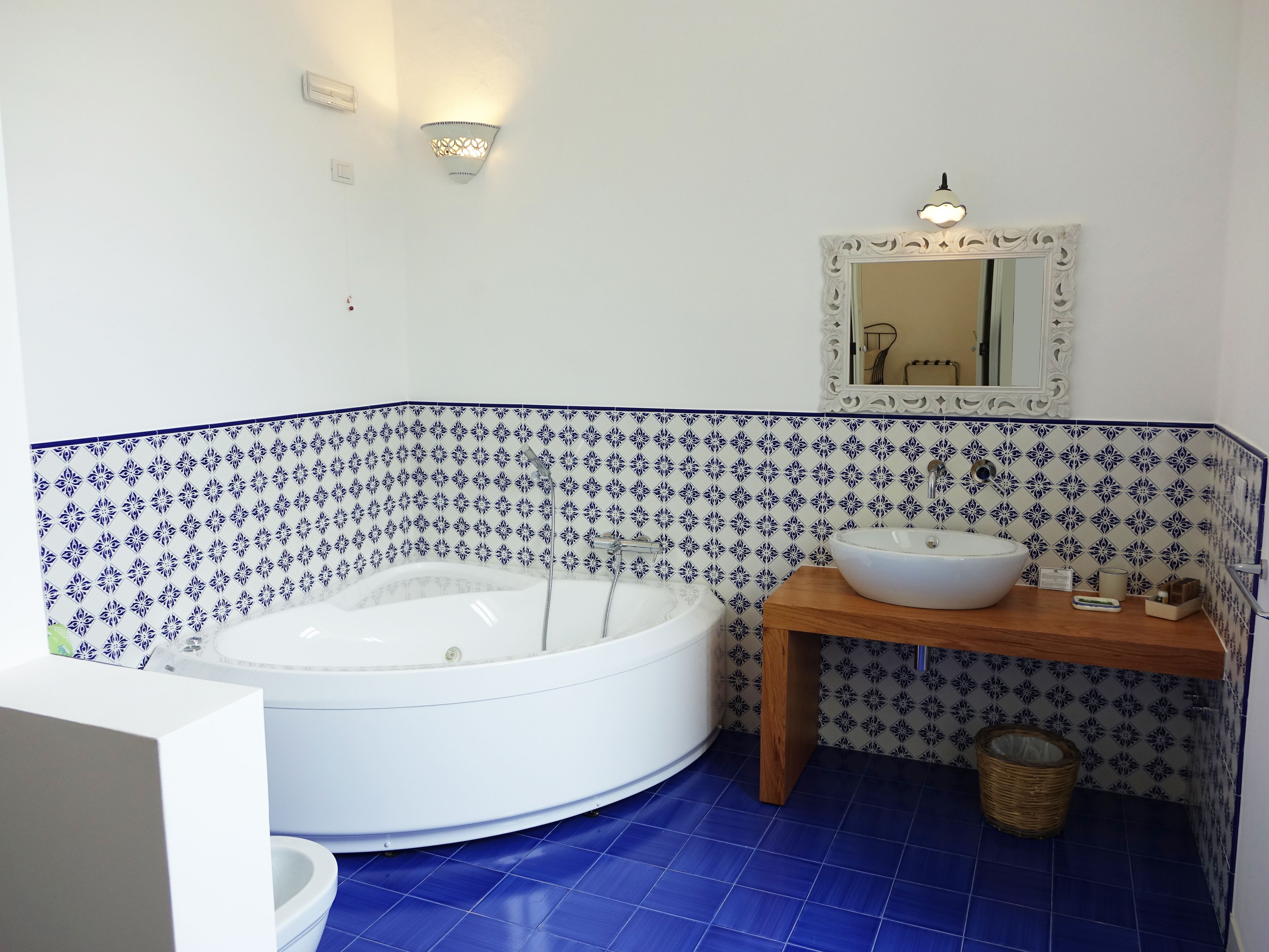 A bathroom with a freestanding bathtub, a wooden vanity with a sink, and a decorative mirror.