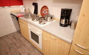 Une cuisine de taille réduite, équipée d’une cuisinière, d’un évier et de différents ustensiles de cuisine.