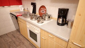 Uma cozinha compacta com fogão, pia e diversas panelas.