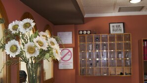 A reception area with a vase of white flowers, a bulletin board, and a display case. - Rey Teodomiro (Orihuela)