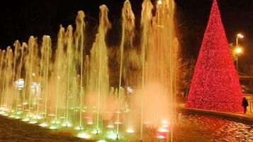 Escena nocturna con un espectáculo de fuentes y un árbol de Navidad rojo.