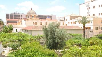 Un patio con un árbol grande, un edificio con cúpula y una estructura moderna al fondo.