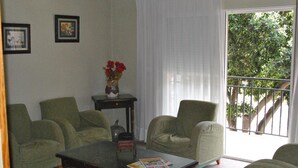 A living room with a sofa, armchairs, a coffee table, and a vase with flowers. - Rey Teodomiro (Orihuela)