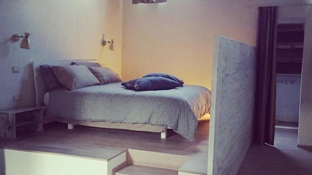 A bedroom with a bed, a small table, and a staircase leading to an upper level. - B&B Relais Druda (Cagli)